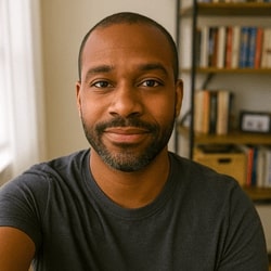 Man wearing a dark gray t-shirt in a room with bookshelves.